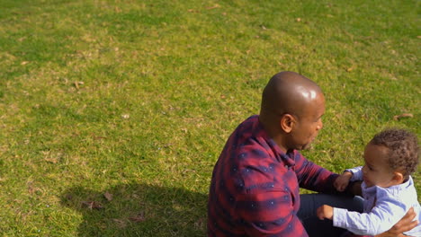 Little-boy-playing-with-his-father-lying-on-grass-in-park